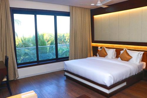 a bedroom with a large bed and a large window at THE GRAND ASTORIA SOMANTH by Shivalaya Darshanam in Somnath