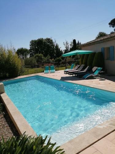 une piscine avec des chaises bleues et une maison dans l'établissement Villa l'Hestia avec piscine à l'Isle-sur-Sorgue, à LʼIsle-sur-la-Sorgue