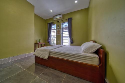 a bedroom with a bed with green walls and a window at Kalinga Art Home Guest House in Siem Reap