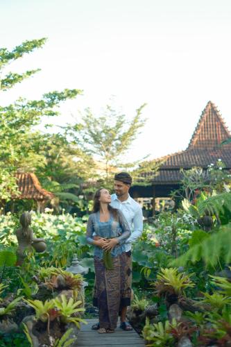 a man and a woman standing in a garden at Ubud Art Resort in Ubud