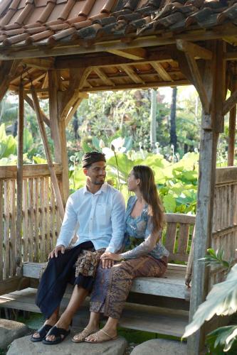 a man and a woman sitting on a bench at Ubud Art Resort in Ubud