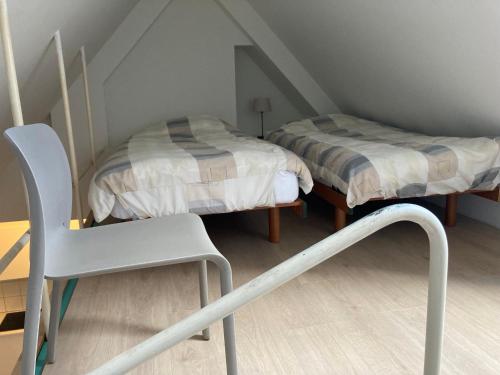 Una pequeña habitación con dos camas y una silla. en Studio Tintin, en Bruselas