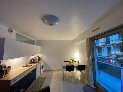 une cuisine avec une table et une grande fenêtre dans l'établissement Le Grand Palais de la Méditerranée Beach Access Apartments - Top Choice In Nice, à Nice