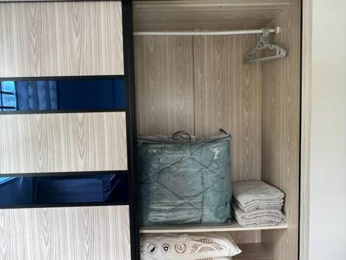 a cabinet with a green bag and some towels at Essential Homestay in Tawau - Bandar Sri Indah in Kampong Parit