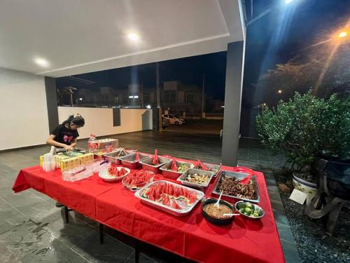 a table with a red table cloth with food on it at Essential Homestay in Tawau - Bandar Sri Indah in Kampong Parit