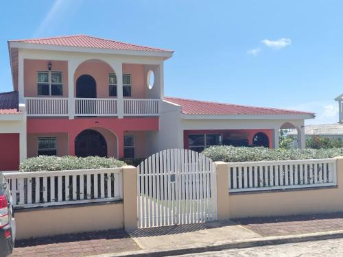 a house with a white fence in front of it at Halfmoon Bay Pink Butterfly in Frigate Bay