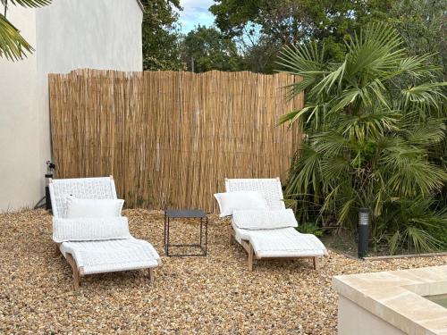 Trois chaises et une table dans une arrière-cour avec une clôture dans l'établissement Le petit Auzon, à Mazan