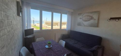 un salon avec un canapé, une table et une fenêtre dans l'établissement residence du bord de mer 9 appartements avec une vraie vue mer, au Tréport
