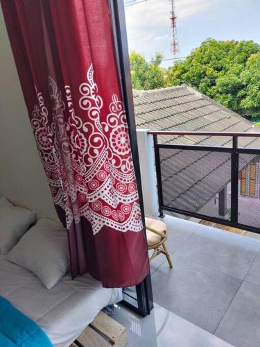 a balcony with a bed and a curtain on a window at Taman Salak Homestay -5BR Entire House in Madiun