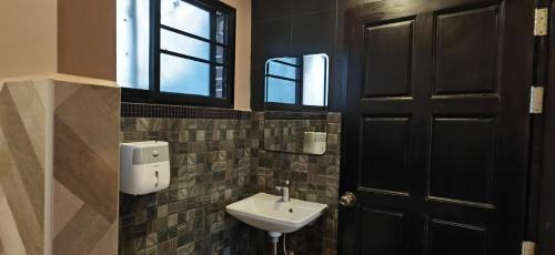 bagno con lavandino e porta nera di Hoh Guesthouse a Chiang Mai