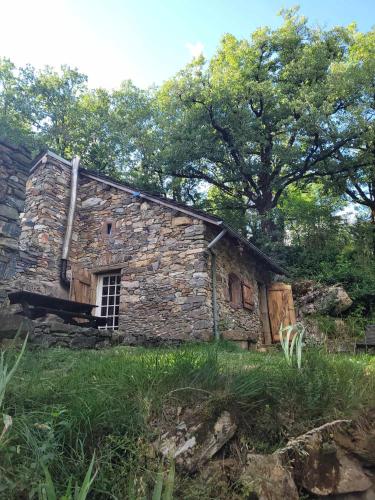 an old stone building with a window in a field at Insolite bergerie dans la forêt in Arnac-sur-Dourdou