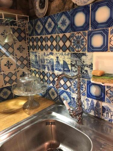a sink in a kitchen with blue and white tiles at Insolite bergerie dans la forêt in Arnac-sur-Dourdou
