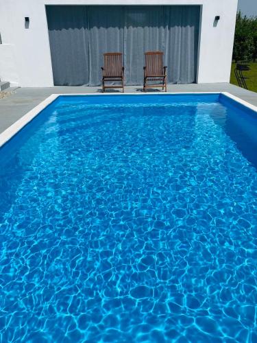 two chairs sitting in a pool with blue water at Holiday House Maya in Mostar
