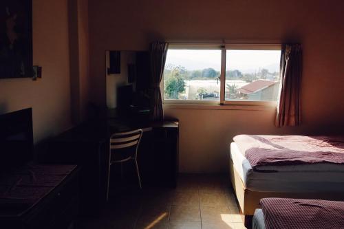 a bedroom with a bed and a desk and a window at Puli Islet Inn in Puli