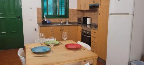 cocina con mesa de madera y copas de vino en Sabbia Suites El Muellito, en Famara
