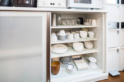 a kitchen cabinet filled with dishes and a microwave at Oceanfront Villa Hale Kahakai プライベートサウナ in Kōembō