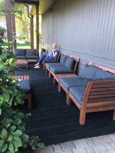 a woman sitting on a porch with benches at Viesu nams Lauciņi in Lāde