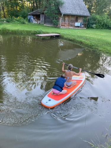 a woman and a child on a paddle board in the water at Viesu nams Lauciņi in Lāde