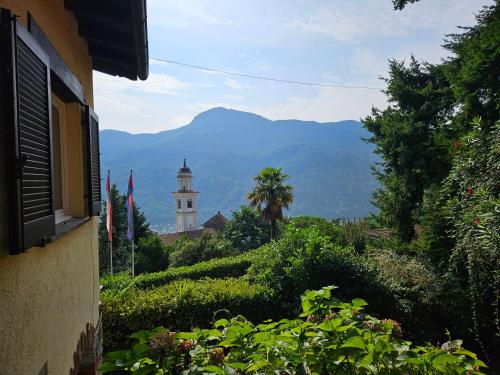 a building and a tower with a mountain in the background at Villetta Poesia in Morcote