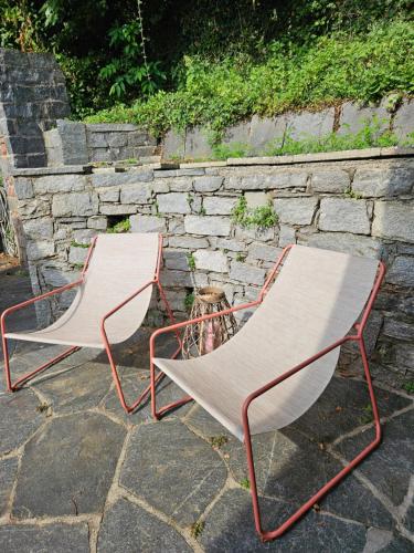 two chairs sitting next to a stone wall at Villetta Poesia in Morcote