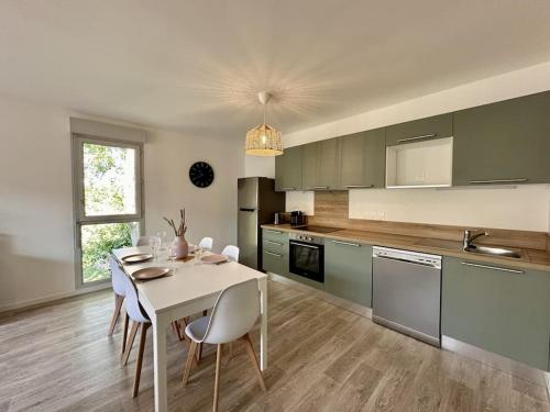 une cuisine avec une table blanche et des chaises dans l'établissement spacieux T3 calme et lumineux, à Carcans