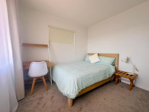 a small bedroom with a bed and a chair at Private room with separate bathroom and carpark in Auckland