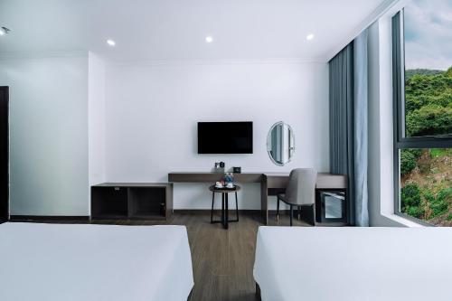 a white room with a desk and a television at Sand Hotel in Cat Ba