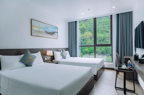 a hotel room with two beds and a window at Sand Hotel in Cat Ba