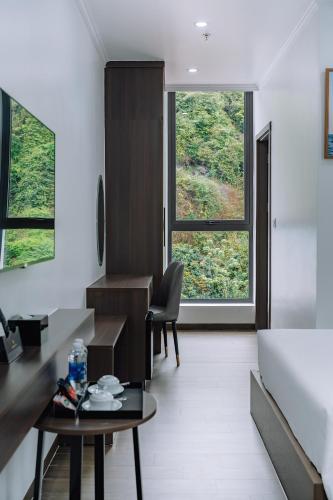 a room with a bed and a desk and a table at Sand Hotel in Cat Ba