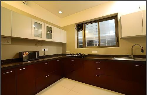 a kitchen with brown cabinets and a window and a microwave at Mizzle Exotica Lonavala in Lonavala