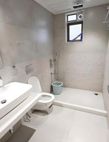 a white bathroom with a toilet and a sink at Mizzle Exotica Lonavala in Lonavala