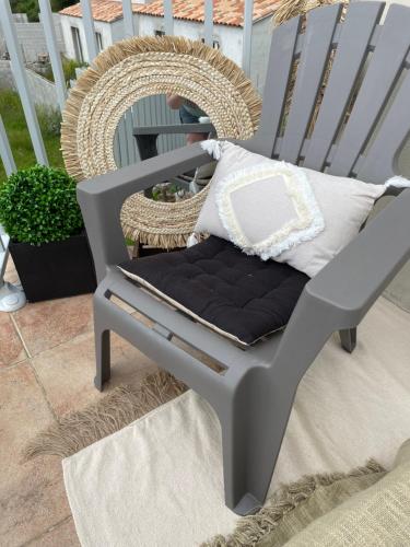 a gray rocking chair with pillows on a patio at Casa Basgiu, chambres avec balcon in Zilia