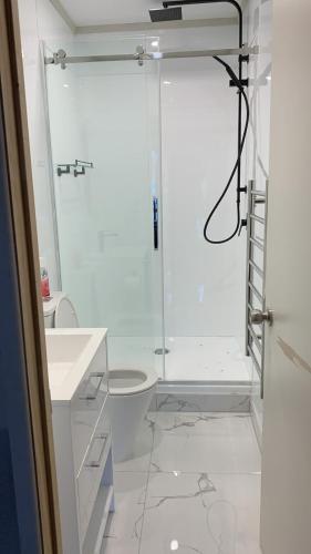 a white bathroom with a shower and a toilet at RUs Terraces in Kauri
