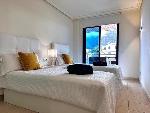 two beds in a bedroom with a large window at Cliffside Residence in Puerto de Santiago