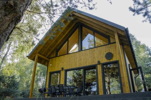 a cabin with glass doors and chairs in a forest at Dom na krańcu lasu in Ostrowy