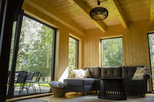 a living room with a couch and large windows at Dom na krańcu lasu in Ostrowy