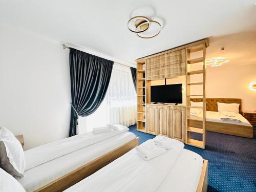 a hotel room with two beds and a flat screen tv at Pensiunea Lara in Râşnov