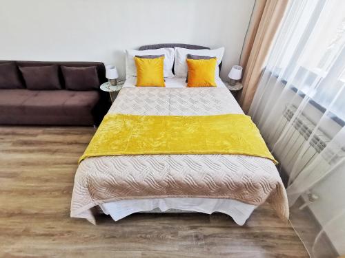 a bedroom with a bed with yellow sheets and a couch at Appartments " Zhetysu-4" in Almaty