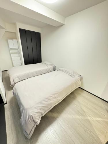 2 letti in una camera con pareti bianche e pavimenti in legno di MA house 701 ad Osaka