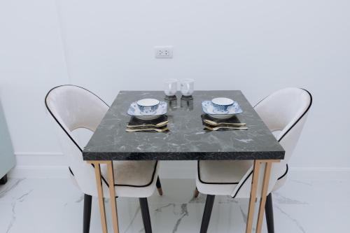 a dining room table with white chairs and a table with glasses at The Empire Tower k in Jomtien Beach