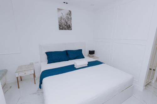 a white room with a bed with blue pillows at The Empire Tower k in Jomtien Beach