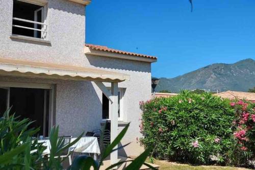 une maison blanche avec une brousse devant elle dans l'établissement Mini villa A Nuciola, à Cervione