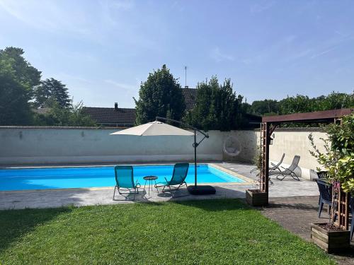 - une piscine avec des chaises, une table et un parasol dans l'établissement L'Alisier Chantant, à Bourron-Marlotte
