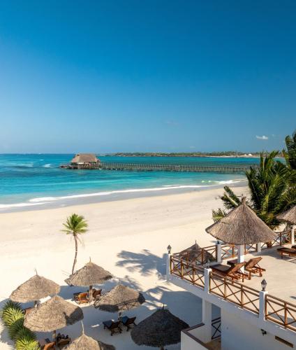 a beach with chairs and umbrellas and the ocean at Karibu Beach Resort - Adults Only in Pongwe