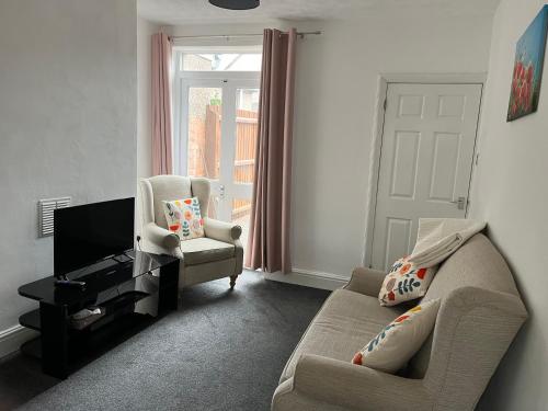 a living room with a couch and a chair and a television at New Bilton House in Rugby