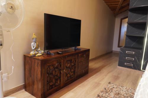 a flat screen tv sitting on top of a wooden entertainment center at Unravel 2BR Attic Floor in Nainital