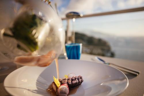 a person is pouring sauce on a plate of food at Villa Fiorella Art Hotel in Massa Lubrense