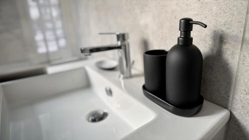 a black soap dispenser sitting on a bathroom sink at Studio8 in Bollate