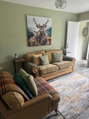 a living room with a couch and a deer painting on the wall at Loch Lomond Riverside Apartments B in Balloch