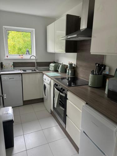 a kitchen with white cabinets and a stove top oven at Loch Lomond Riverside Apartments B in Balloch